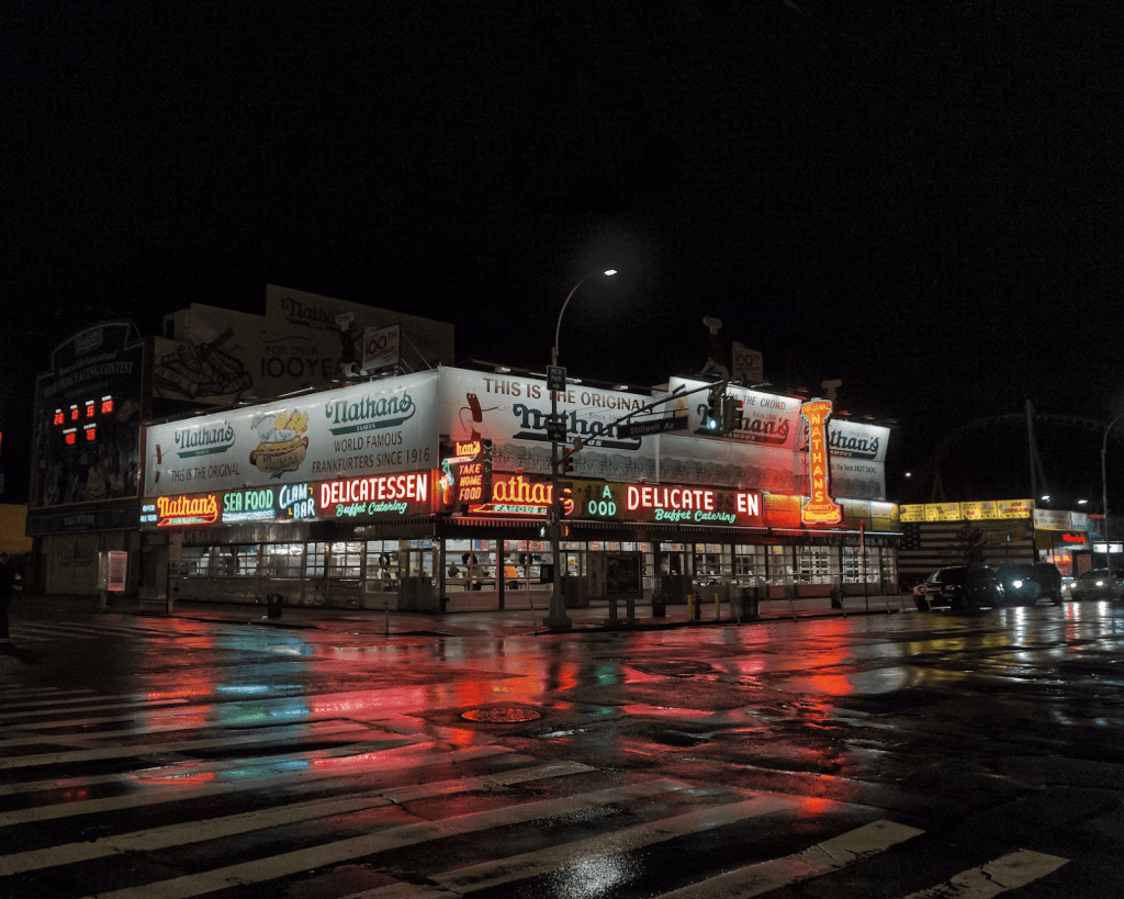 Image of coney island at night with neon lights and large signs
