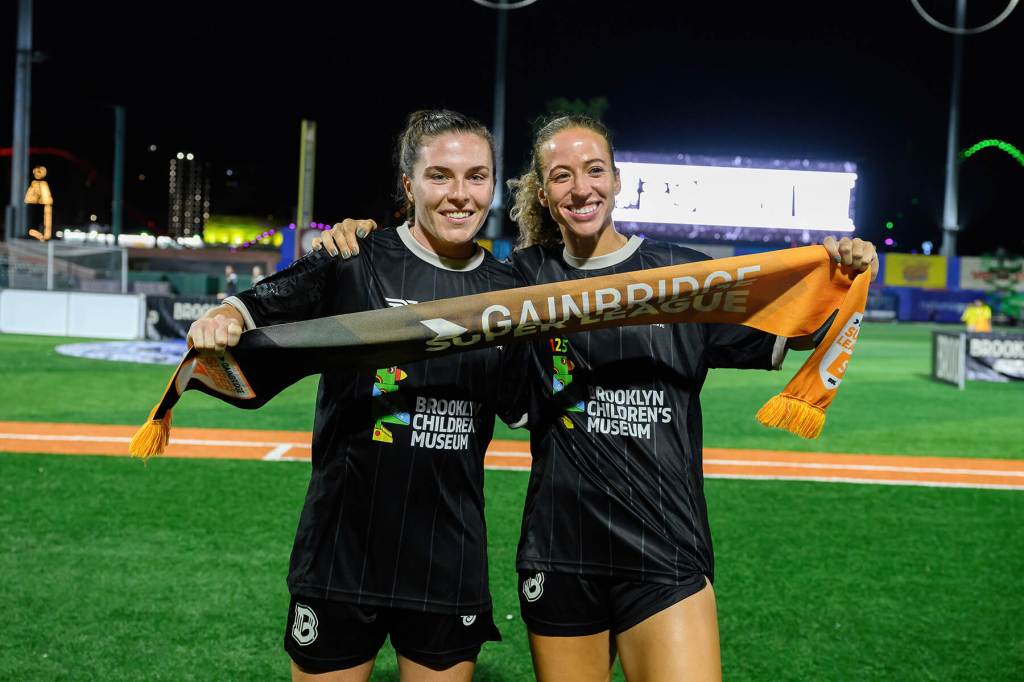 Catherine Zimmerman and Allison Williams hold a Gainbridge Super League banner after Brooklyn's 2-1 win over Tampa Bay on August 23, 2025
