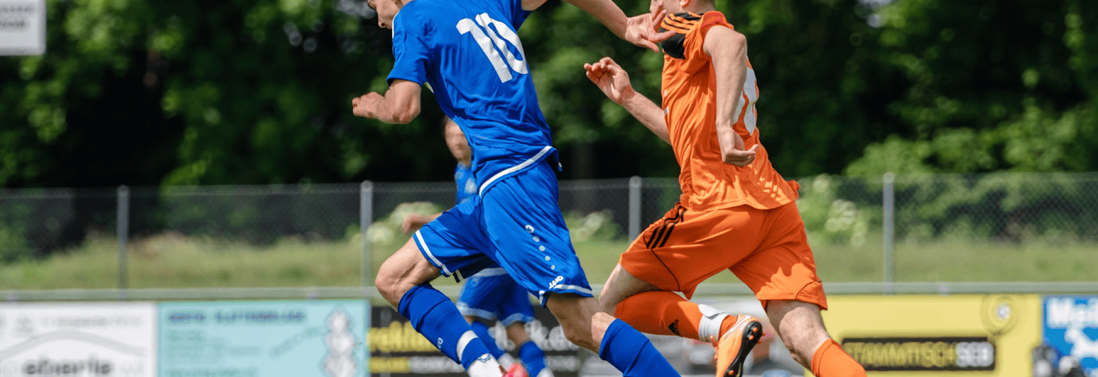 Image of two male soccer players racing for a ball during a match