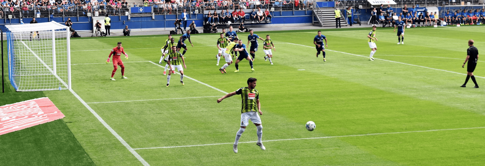 Image of a live soccer match where players race for a ball in a packed stadium