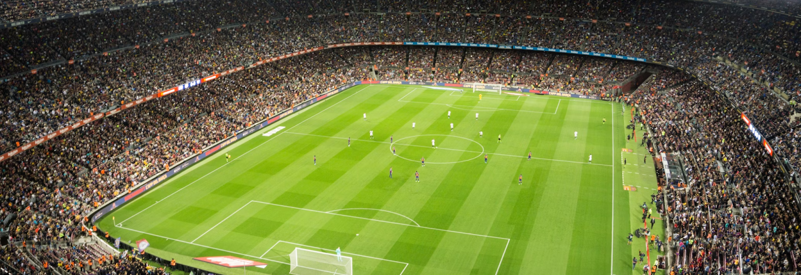 Image of a large soccer field indoors with lights illuminating the field and crowd