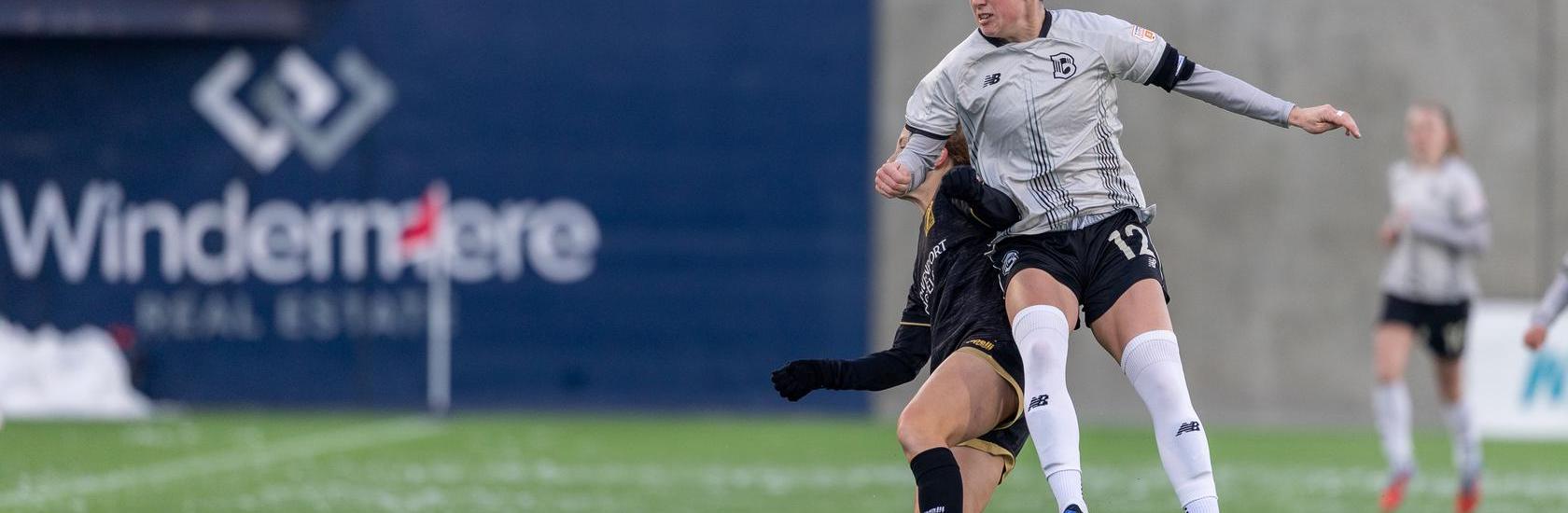 Brooklyn FC defender Hope Breslin heads the ball while contesting an aerial challenge against an opponent during a match.