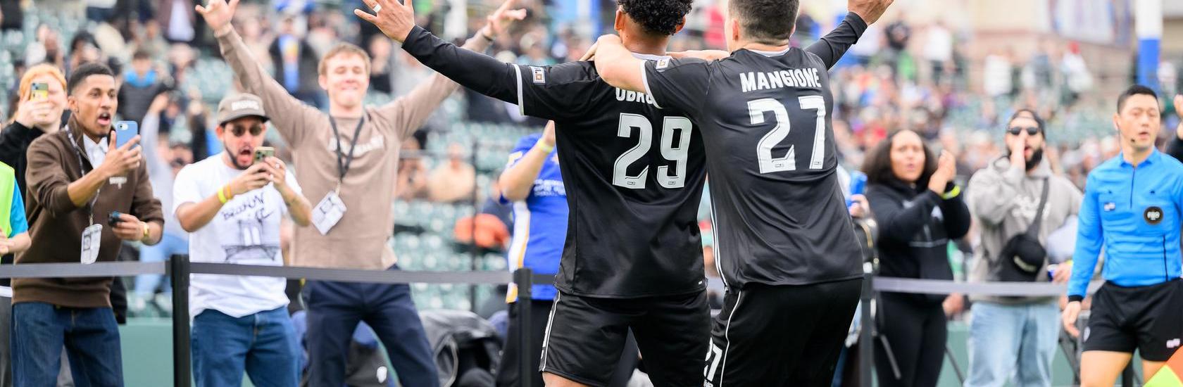 Brooklyn FC men players Juan Carlos Obregón Jr. and Peter Mangione celebrate with supporters after a goal at Maimonides Park.