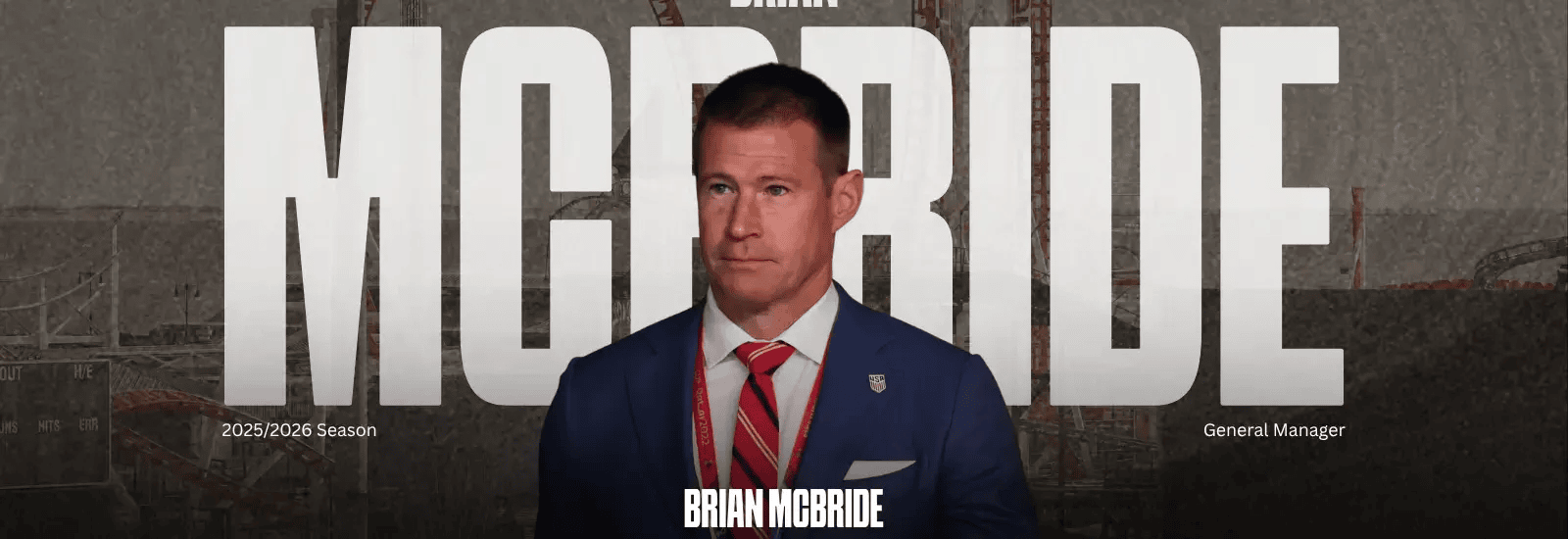 Brian McBride stands at a podium for Brooklyn FC