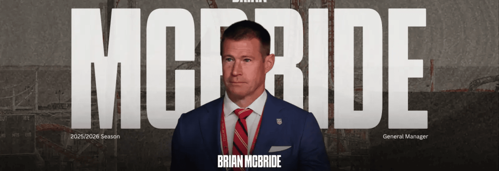 Brian McBride stands at a podium for Brooklyn FC